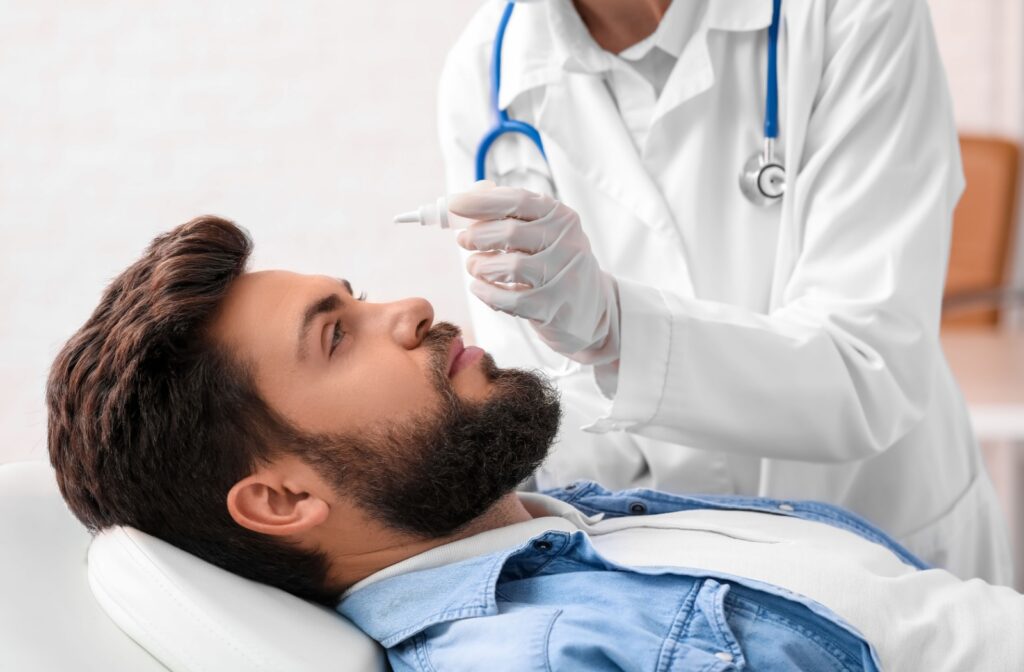 Man receiving eye drops from a doctor during an eye exam.