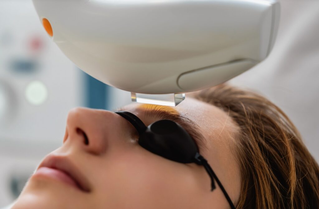 Patient receiving IPL dry eye treatment with protective eyewear and light therapy device.