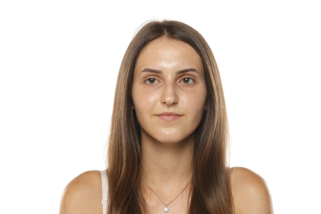 A young woman with long brown hair looking straight at the camera, shown against a white background.